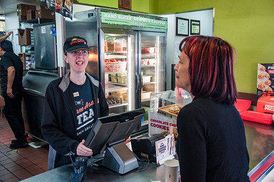 TCC Associate working as a cashier at a fast food restaurant serving a customer.