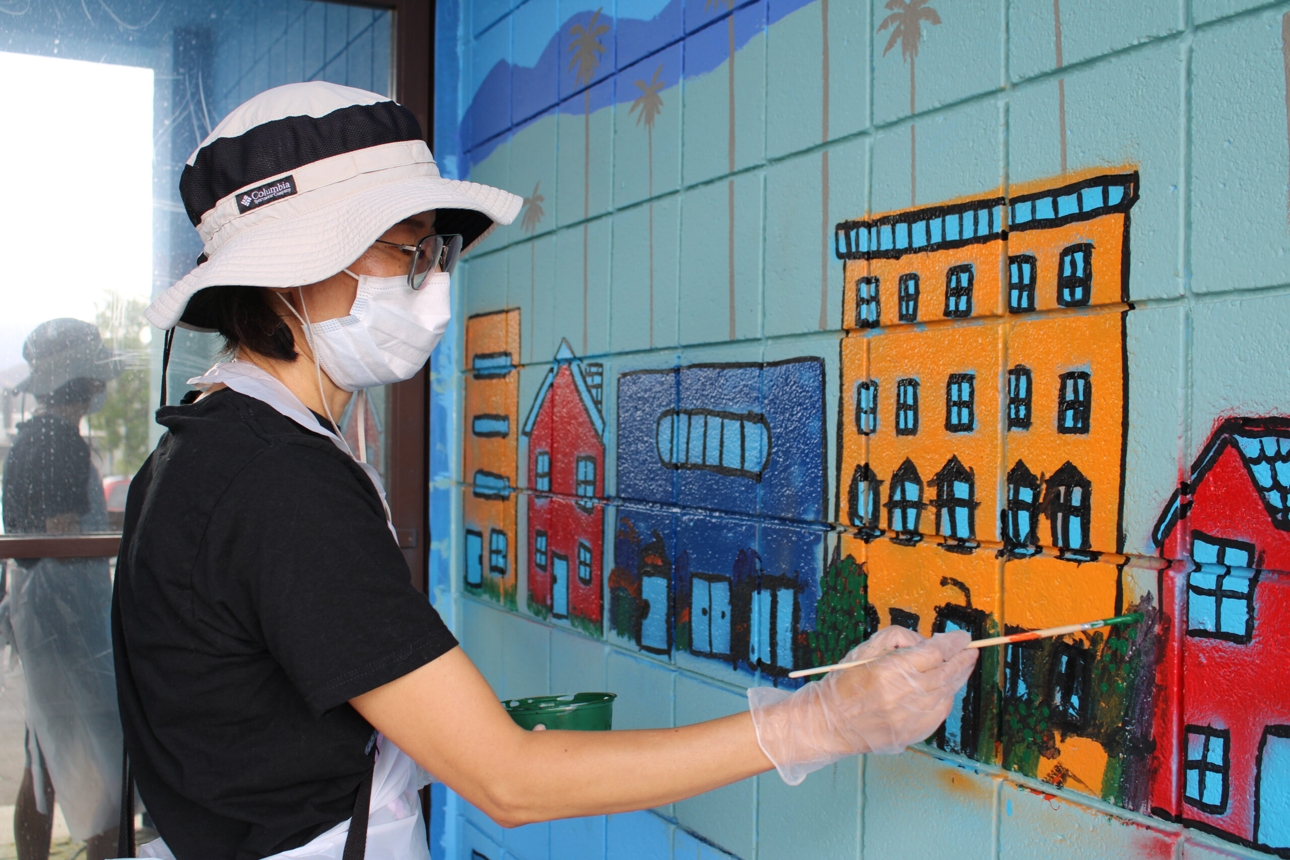 Woman paints the mural on the building