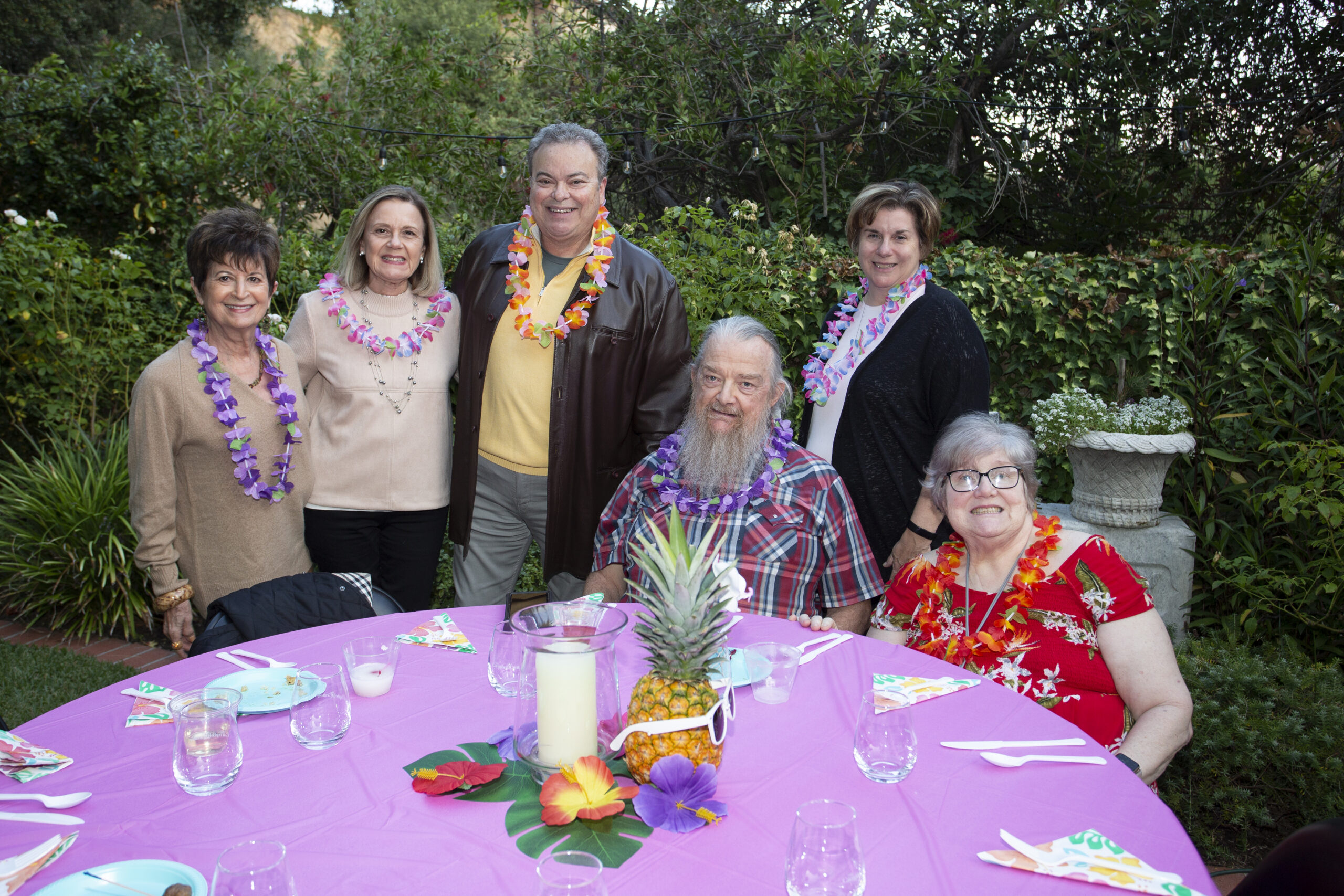 Luau guests group photo around a pink table